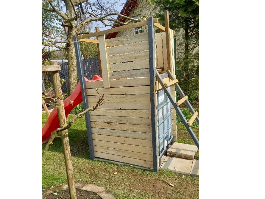 Spielhaus aus Holz mit roter Rutsche