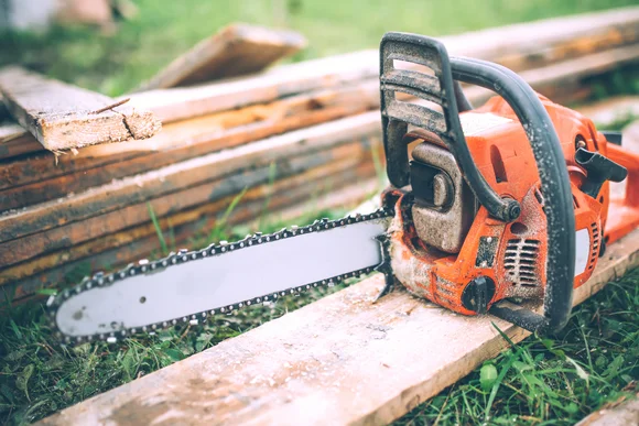 Eine Kettensäge liegt auf Holzbrettern.