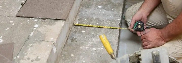 Person misst Fliesen auf einer Treppe aus