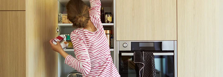 Person sucht in einem Küchenschrank