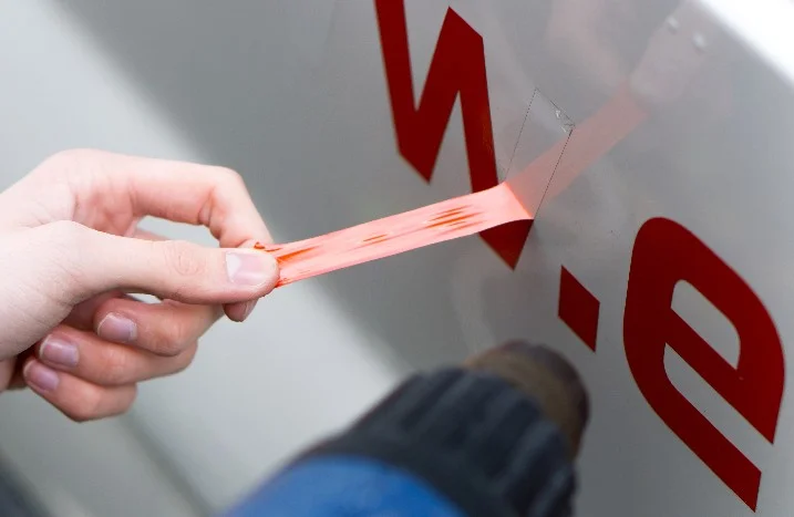 Hand entfernt Klebeband von Auto