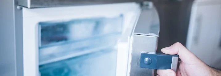 Hand öffnet Kühlschranktür