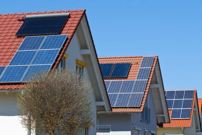 Mehrere Hausdächer mit installierten Photovoltaik- und Solarthermieanlagen.