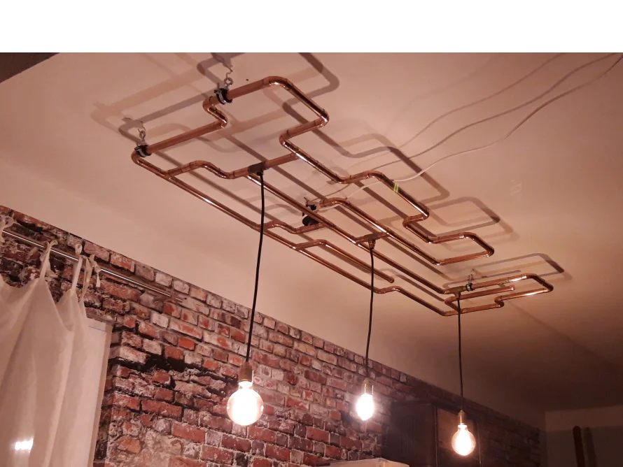 Kupferrohrlampe an einer Ziegelwand
