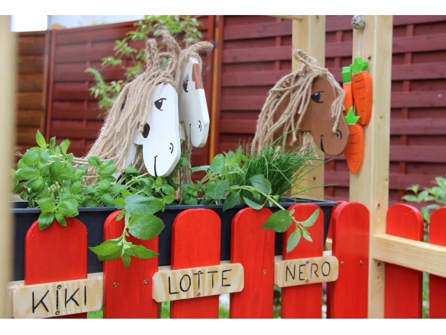 Holzpferde und Kräuter in einem Hochbeet