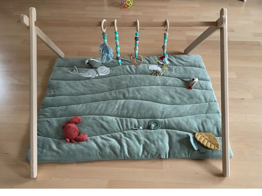 Ein Baby-Spielbogen aus Holz mit Spielzeug.