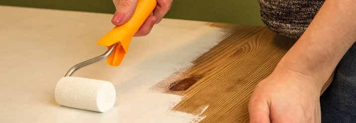 Person streicht Holztisch weiß