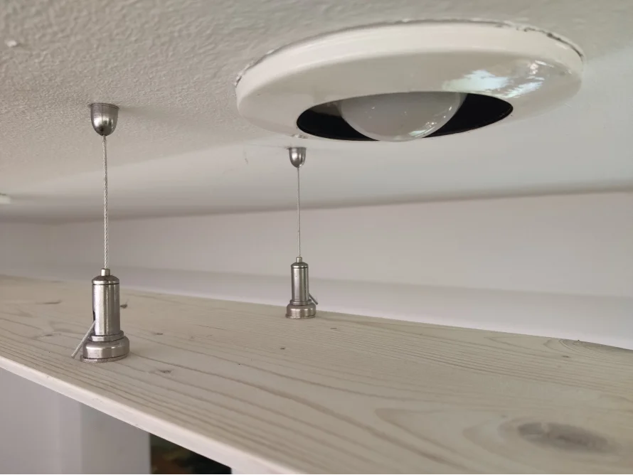 Drei Haken an Drähten hängen an der Decke