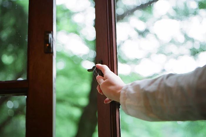 Hand öffnet Fenster mit Fenstergriff