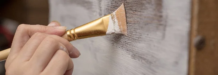 Hand streicht Holz weiß