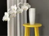 Weiße Orchidee in Vase auf gelbem Hocker