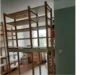 Ein hohes Holzregal steht in einem Zimmer.
