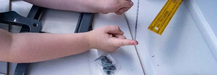 Zwei Personen bauen eine Katzenklappe mit Zollstock ein.