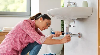 Person tauscht Siphon unter Spüle