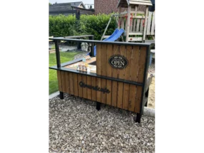 Ein selbstgebautes Strandcafé aus Holz für Kinder im Garten.