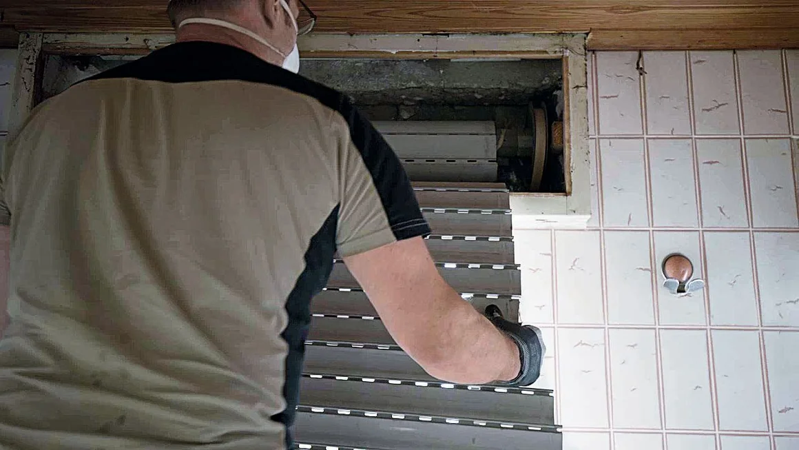 Person montiert einen Rollladen.