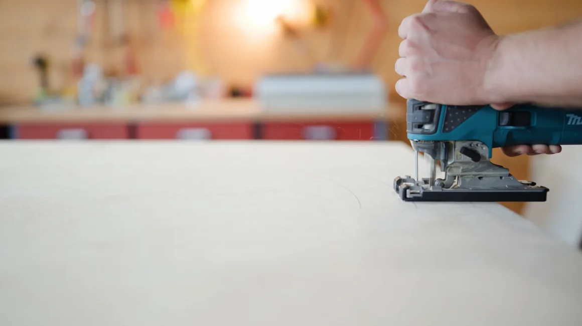 Person sägt Holzplatte mit Stichsäge