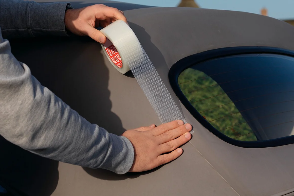 Person klebt durchsichtiges Klebeband auf Auto