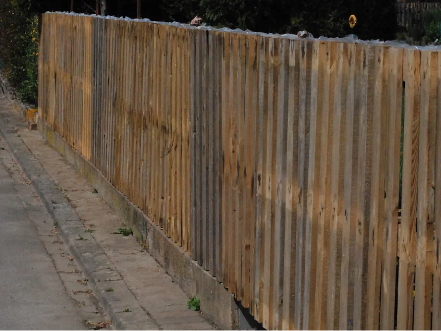 Hühnerdrahtzaun neben einem Gehweg.