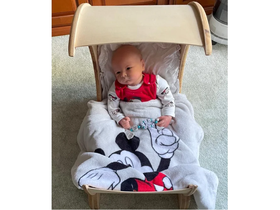 Baby in einer Wiege mit Micky-Maus-Decke