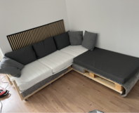 Selbstgebautes Ecksofa aus Holz mit weißen Matratzen und grauen Kissen