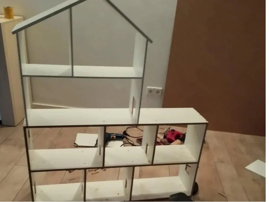 Ein großes, weißes Puppenhaus-Regal im Aufbau mit Werkzeug.