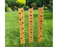 Drei hohe Holzlatten mit bunten Glaskreisen im Rasen