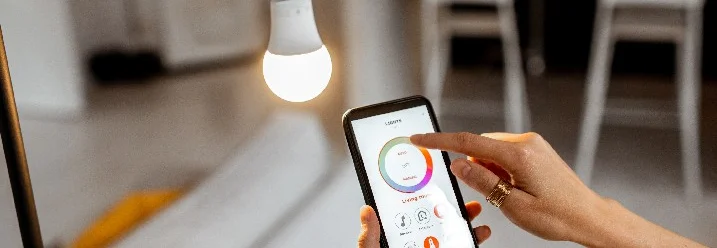 Person steuert Glühbirne mit Smartphone