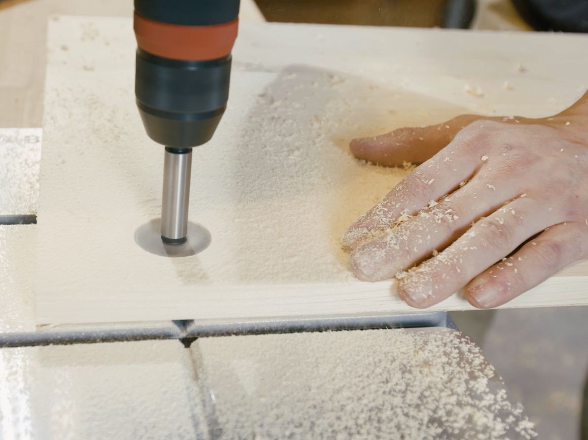 Bohrmaschine bohrt Loch in Holzplatte