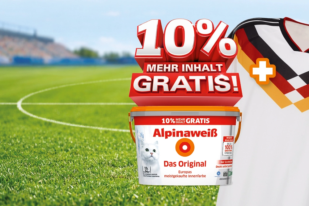 Ein Eimer weißer Farbe und ein Fußballtrikot stehen vor einem Fußballfeld.