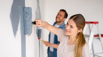 Personen streichen Wand mit Farbe