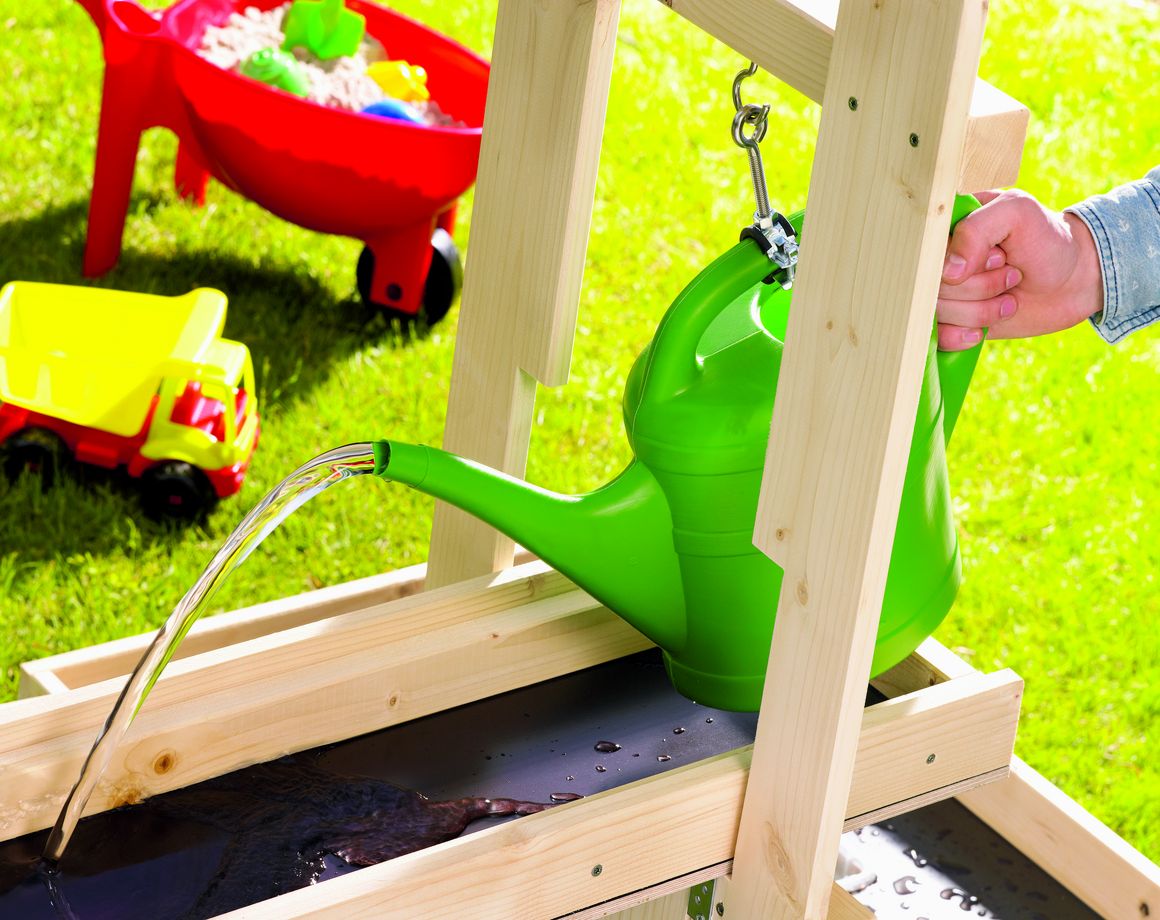 Person giesst Wasser in ein Holzgerüst