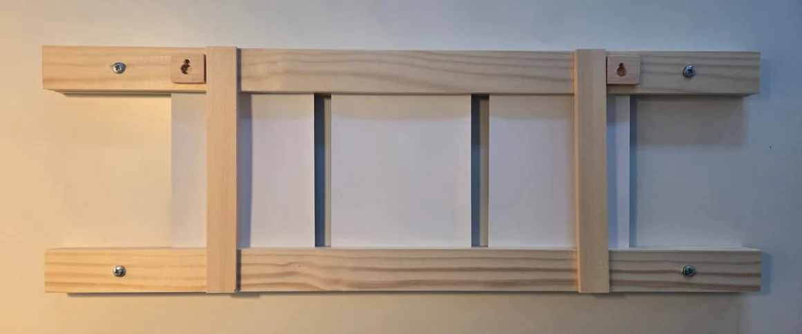 Die Rückseite eines hölzernen Keilrahmens mit Aufhängern an einer Wand.