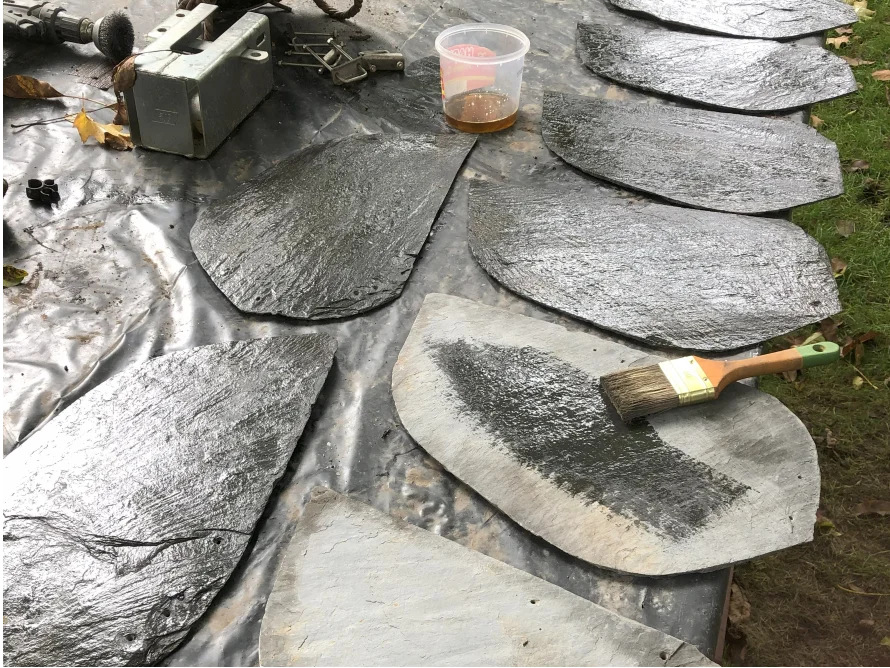 Schieferplatten werden mit einem Pinsel bestrichen