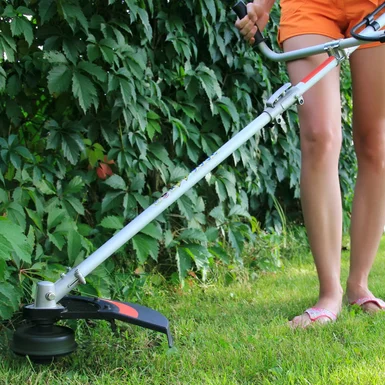 Person trimmt Rasen mit Freischneider