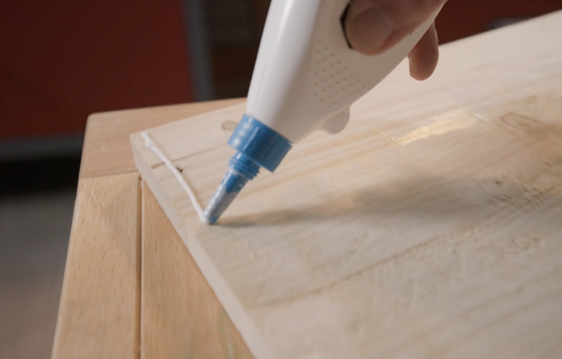 Person verklebt Holz mit Klebstoffpistole