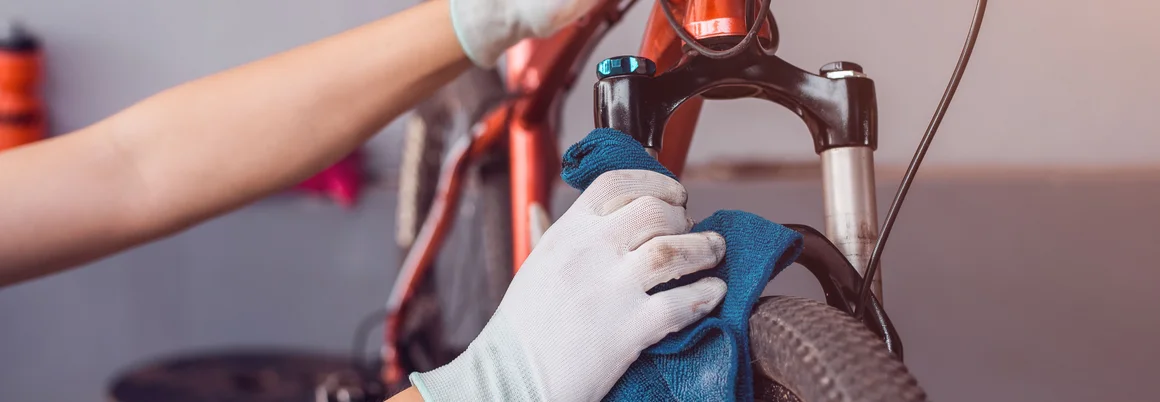 Person reinigt Fahrradgabel mit Tuch