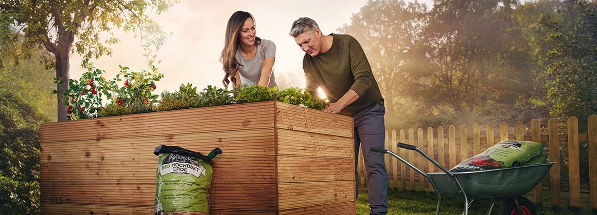 Ana und Bastian bepflanzen ein Hochbeet mit Tomaten