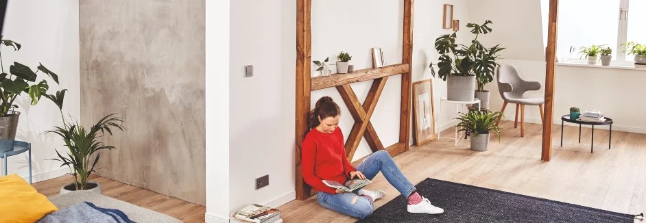 Person liest in einem Zimmer mit Pflanzen