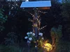 Ein mit Lichterketten und Blumen dekoriertes Vogelhaus bei Nacht.