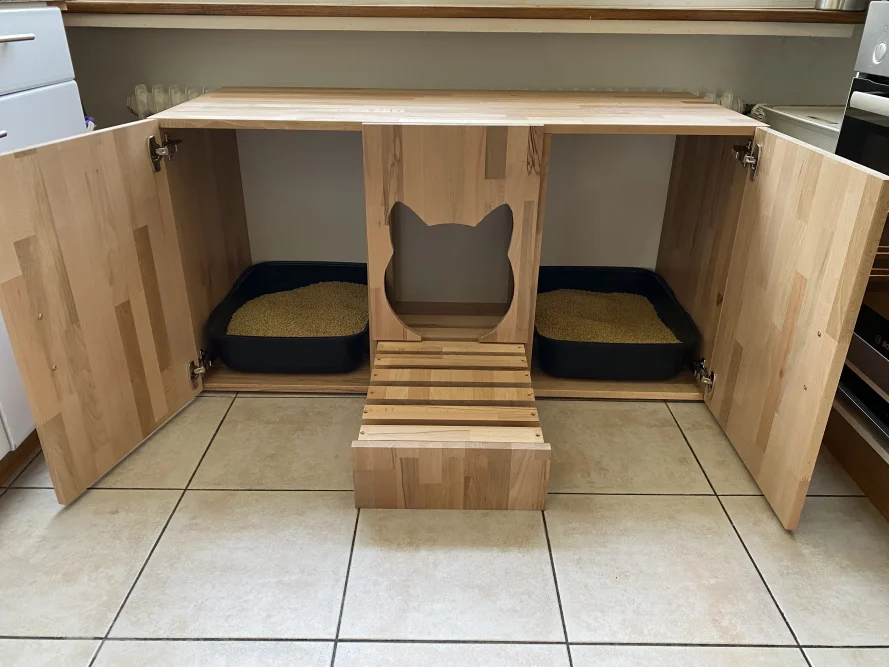 Ein hölzerner Katzentoilettenunterschrank mit zwei Katzentoiletten im Inneren.