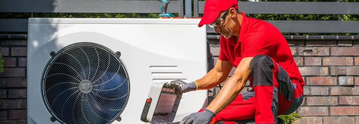 Person repariert Wärmepumpe mit Werkzeugkasten.