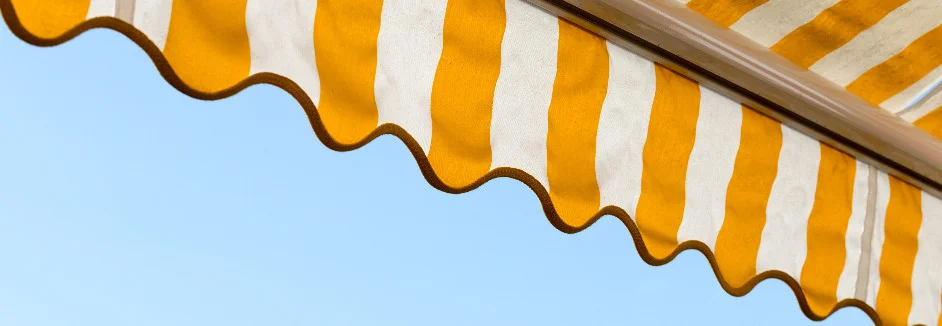 Gelb-weiße Markise vor blauem Himmel