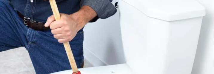 Person benutzt Pümpel in Toilette