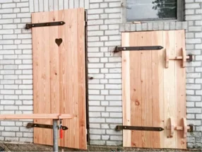 Zwei Holztüren mit Beschlägen an weißer Ziegelwand