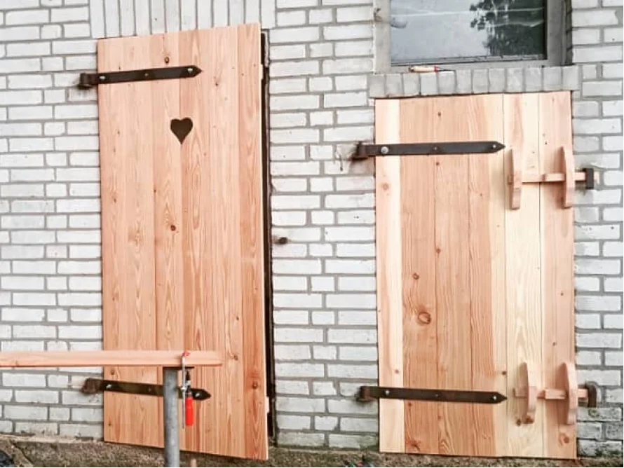 Zwei Holztüren mit Beschlägen an weißer Ziegelwand