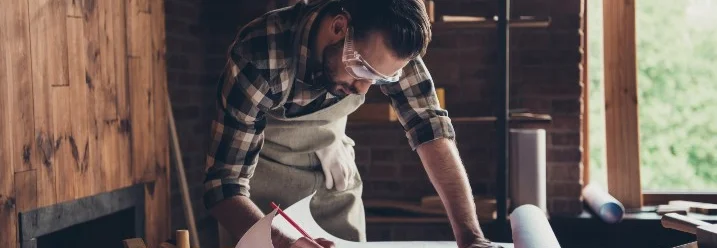 Person beugt sich über Bauplan