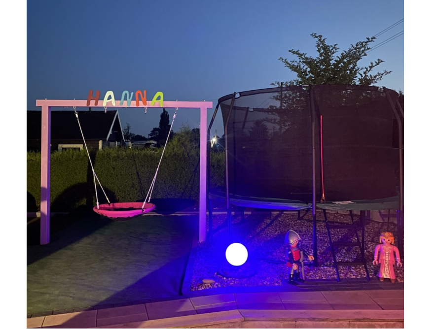 Schaukel und Trampolin in einem Garten bei Nacht