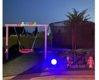 Schaukel und Trampolin in einem Garten bei Nacht