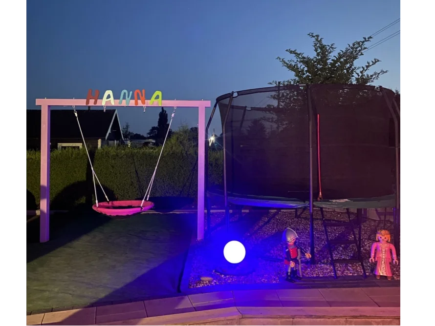 Schaukel und Trampolin in einem Garten bei Nacht